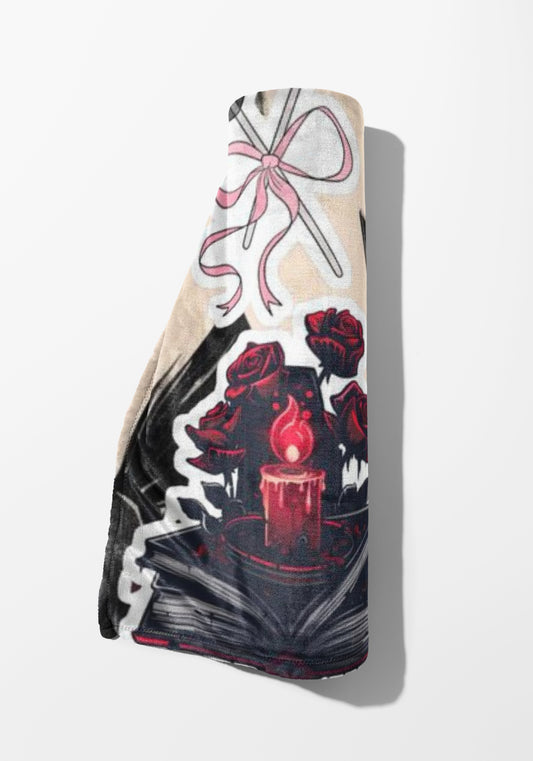 Rolled blanket with a design of red roses, a lit candle, and a pink ribbon.