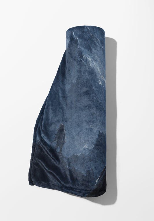 Rolled dark blue blanket with a fantasy landscape and warrior print.