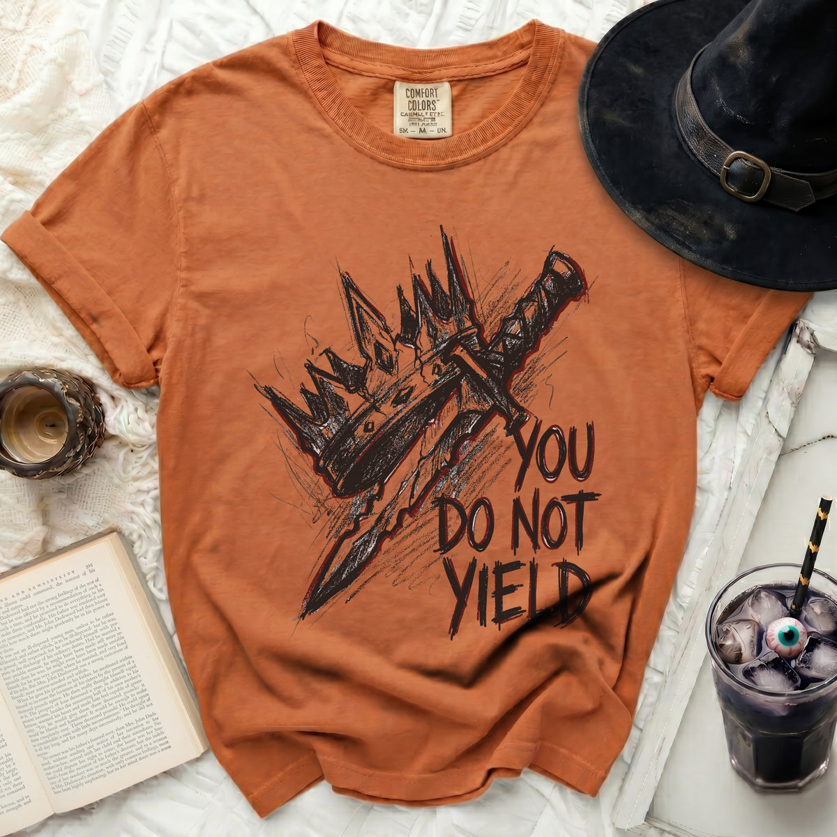 Orange t-shirt with a sketch of a sword and crown, and text "YOU DO NOT YIELD".