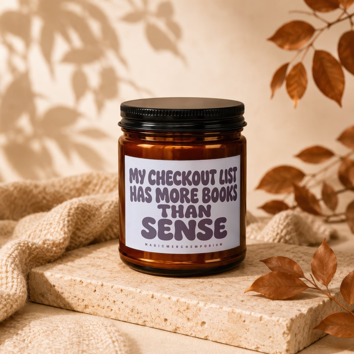 Amber jar candle with black lid reading "MY CHECKOUT LIST HAS MORE BOOKS THAN SENSE."