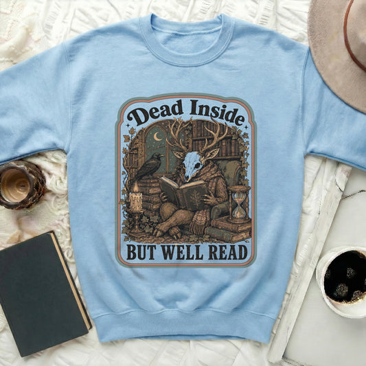 Light blue sweatshirt with a graphic featuring a deer skull reading among books, with text "Dead Inside But Well Read".