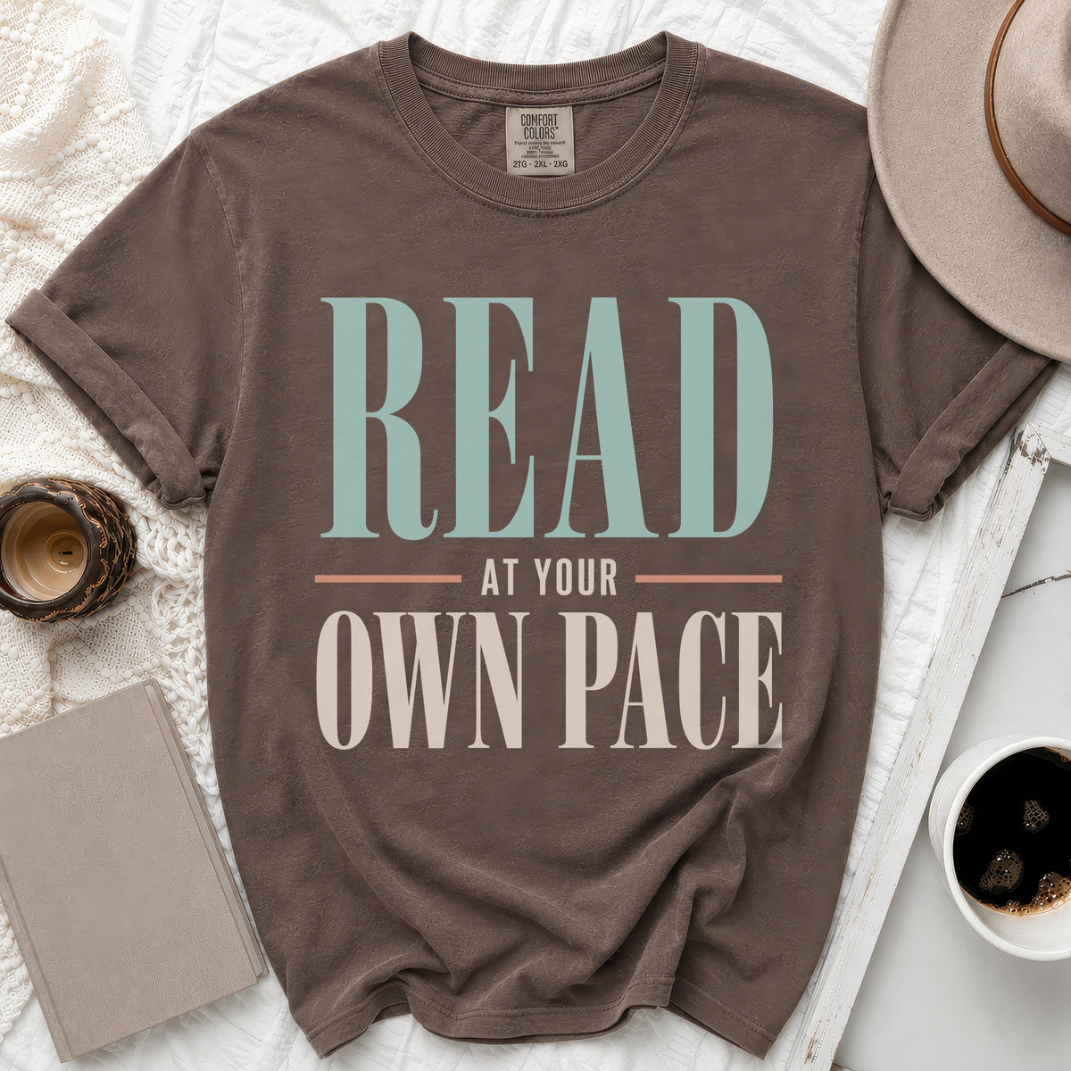 Brown t-shirt with "READ AT YOUR OWN PACE" text in pastel green and cream.
