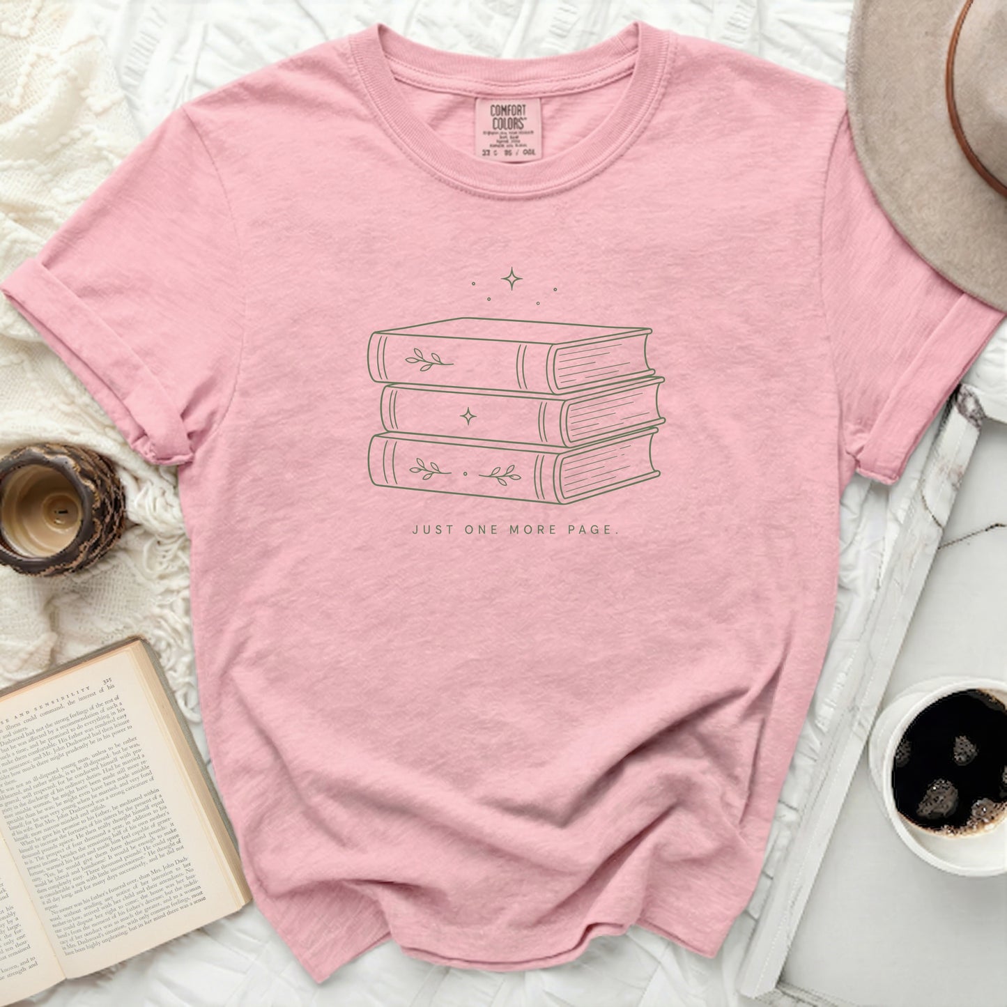 Pink t-shirt with stacked books and text "JUST ONE MORE PAGE."