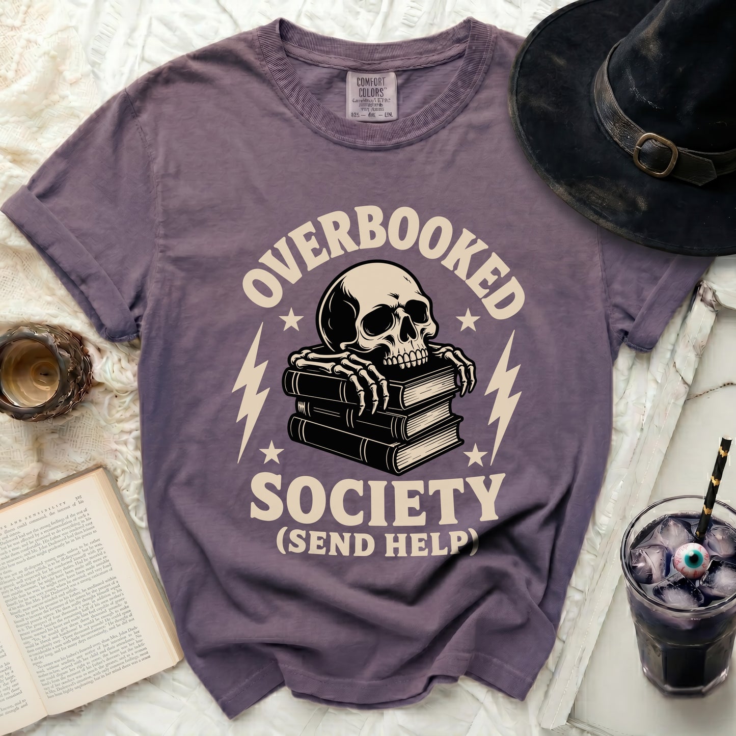 Purple t-shirt with "Overbooked Society (Send Help)" and skeleton on books graphic.