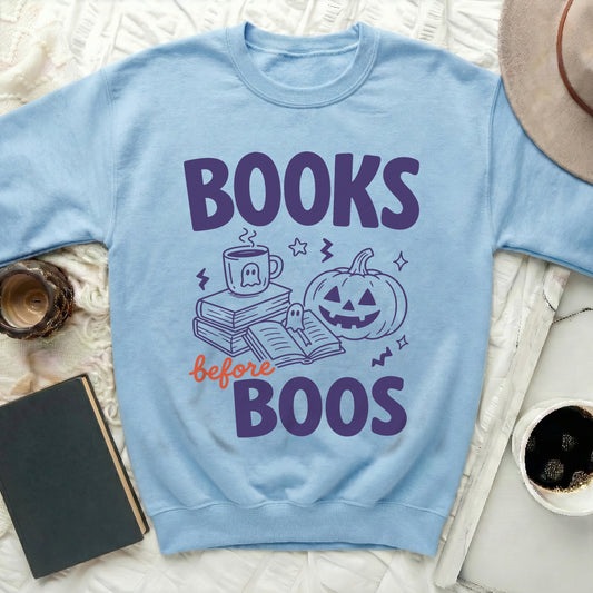 Light blue sweatshirt with "Books before Boos" Halloween graphic.