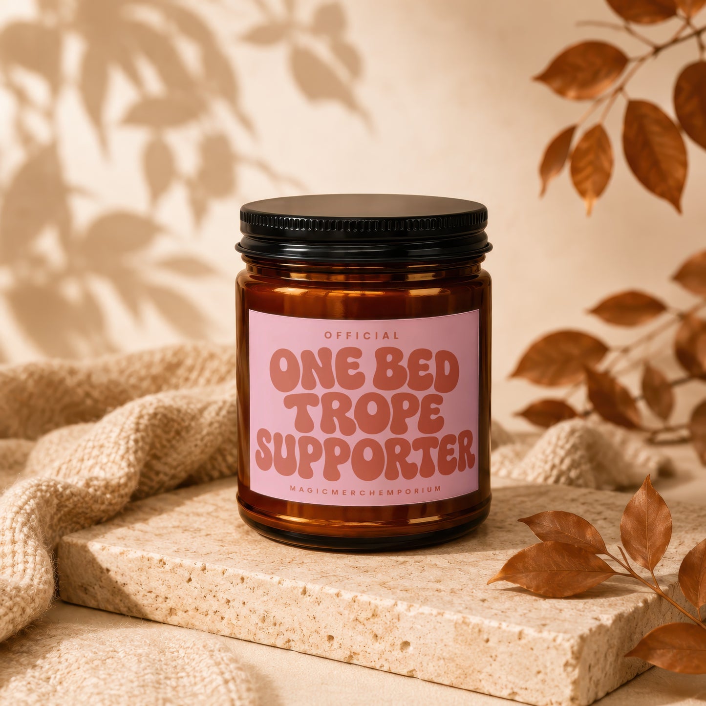 Amber glass candle with pink label reading "Official One Bed Trope Supporter"