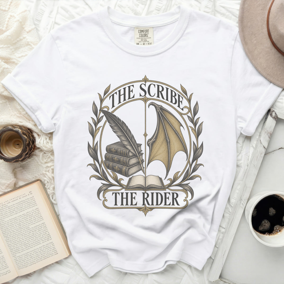 White t-shirt with a circular graphic featuring books, quill, and dragon wings.