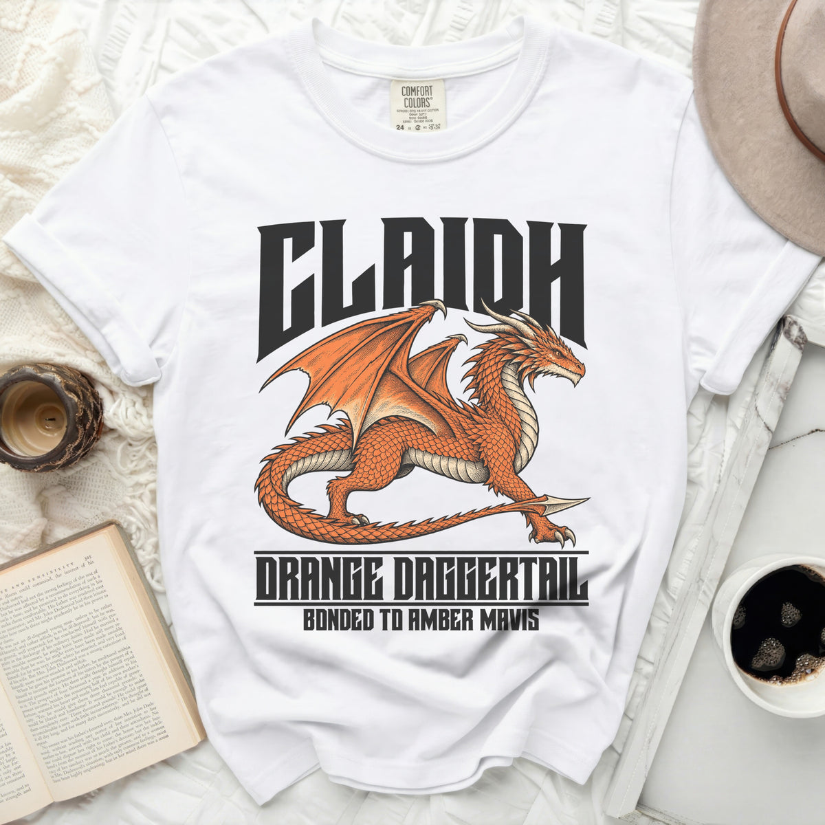 White t-shirt with an orange dragon graphic and text "CLAIDH ORANGE DAGGERTAIL BONDED TO AMBER MAVIS".