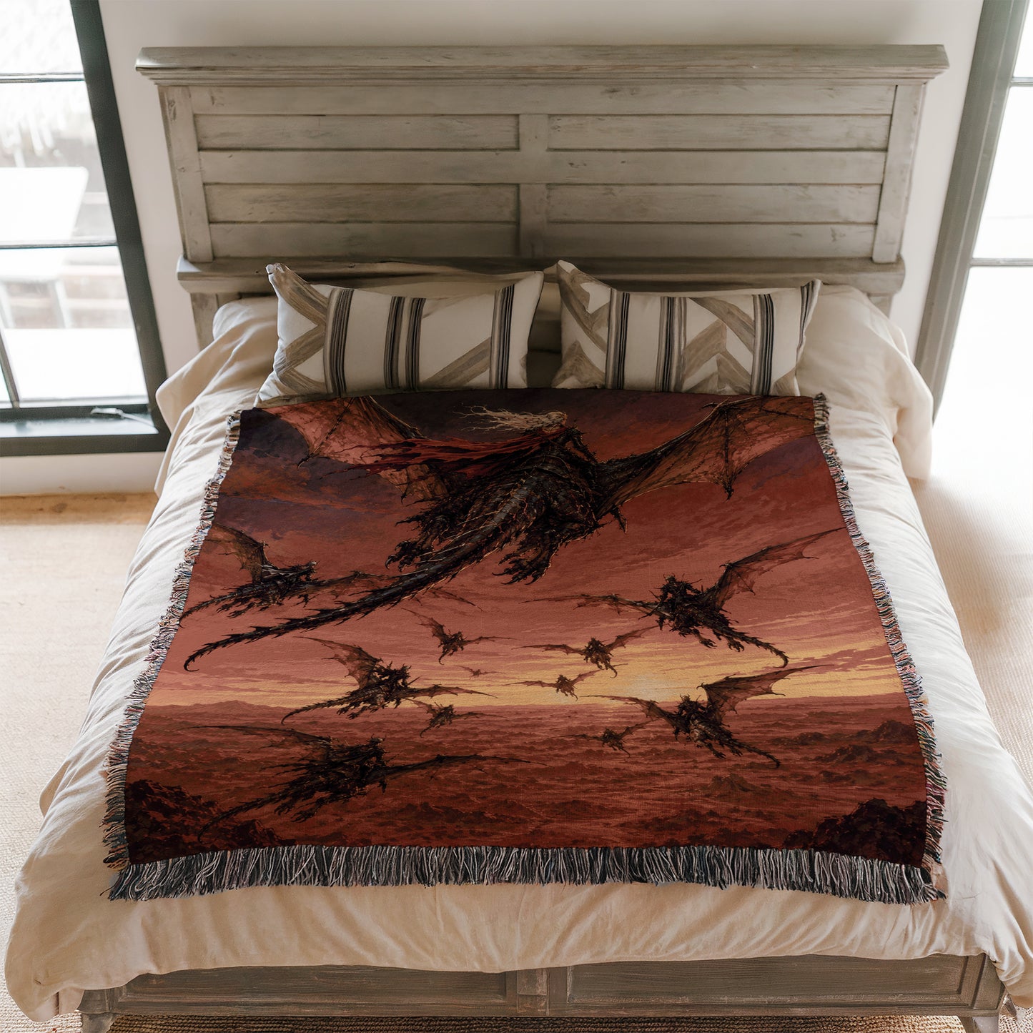 a bed with a large, colorful dragon-themed blanket on it. The blanket has a striking red and orange color scheme and depicts a group of dragons flying across a sunset-like sky.