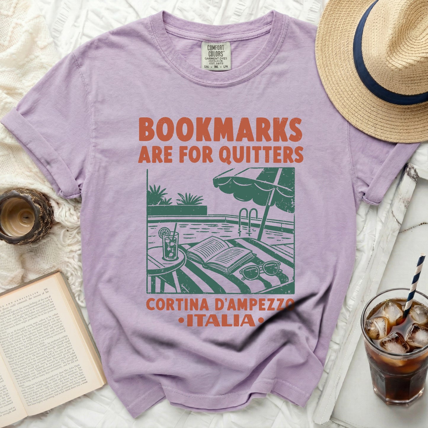 Purple t-shirt with "Bookmarks are for quitters" and pool scene graphic.