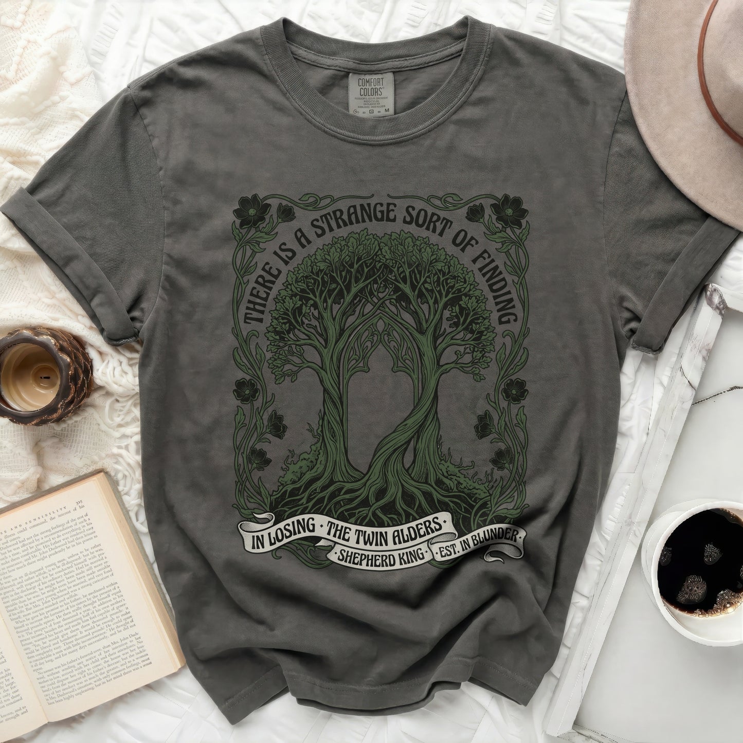 Dark grey t-shirt with intertwined trees and text "There is a strange sort of finding".