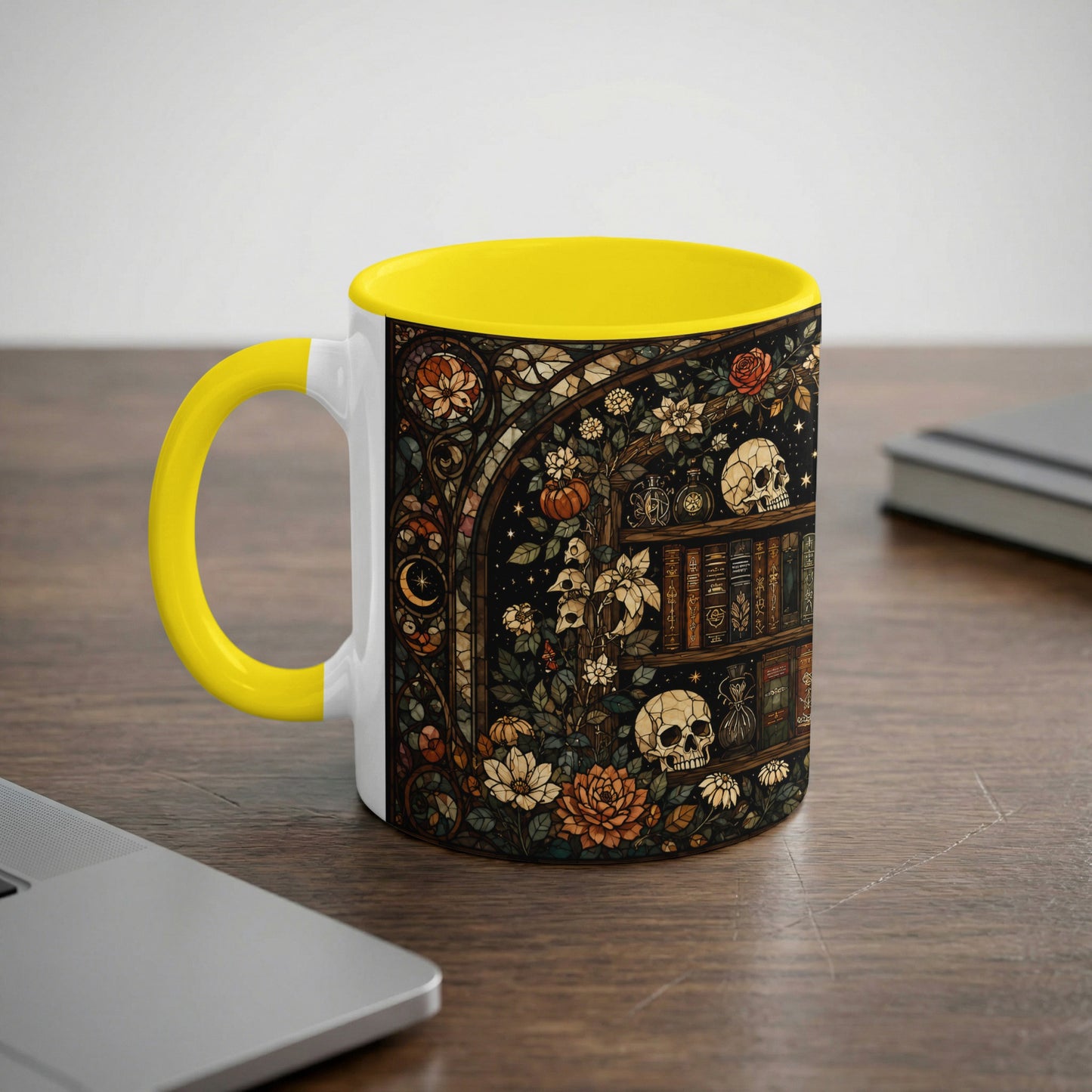 Yellow-handled mug with spooky stained-glass design of skulls, books, and flowers.