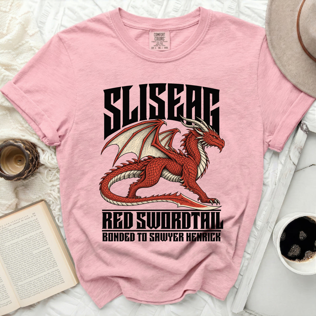 Pink t-shirt with a red dragon graphic and text: "SLISEAG RED SWORDTAIL BONDED TO SAWYER HENRICK".