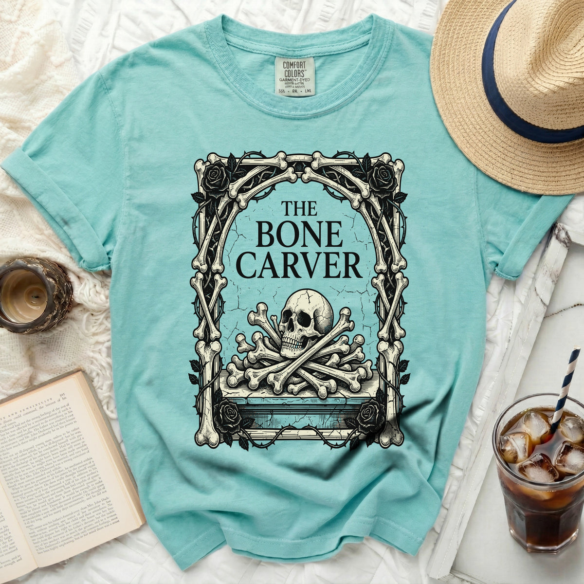 Teal t-shirt with "The Bone Carver" text and skull graphic.