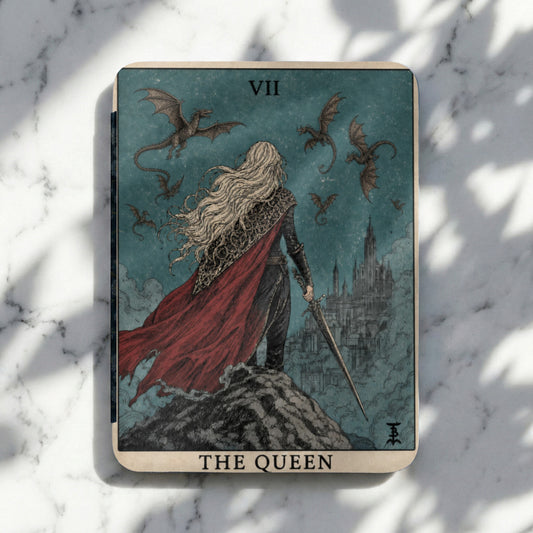Tarot card featuring a blonde queen with a red cape and sword, facing dragons and a castle.