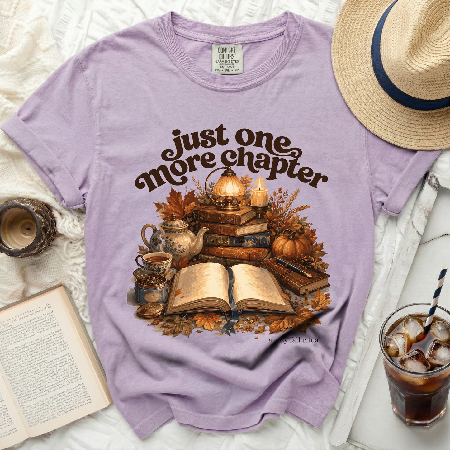 Purple t-shirt with "just one more chapter" and fall illustration.
