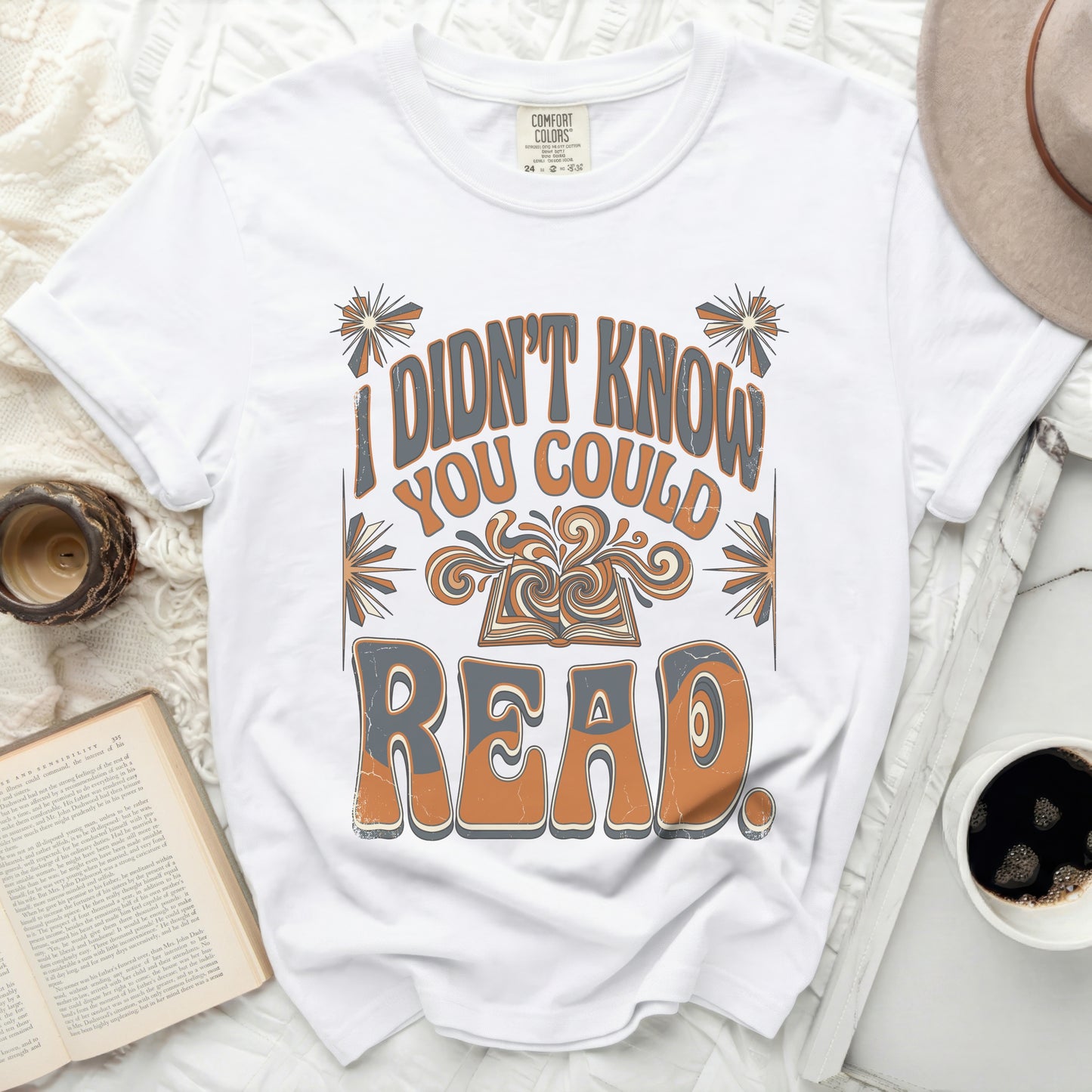White t-shirt with "I didn't know you could read" graphic and open book.