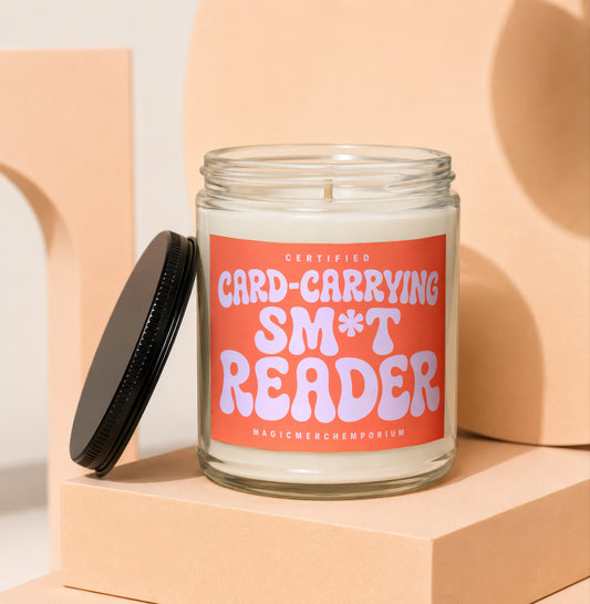 Glass candle with orange label reading "Certified Card-Carrying Sm*t Reader".