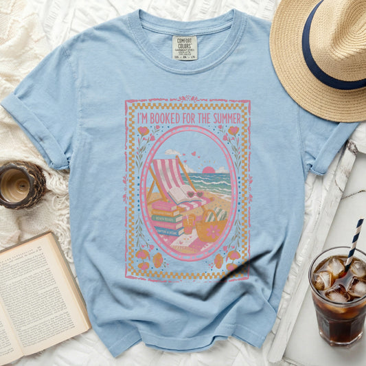 Light blue t-shirt with "I'm Booked for the Summer" graphic of beach items and books.