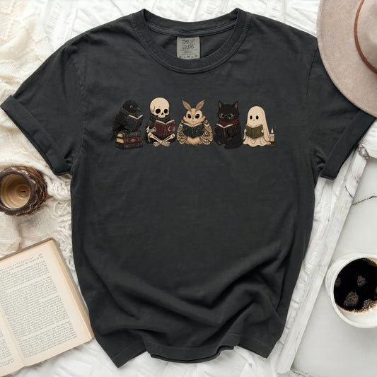 Dark t-shirt with illustrated crow, skeleton, moth, cat, and ghost reading books.
