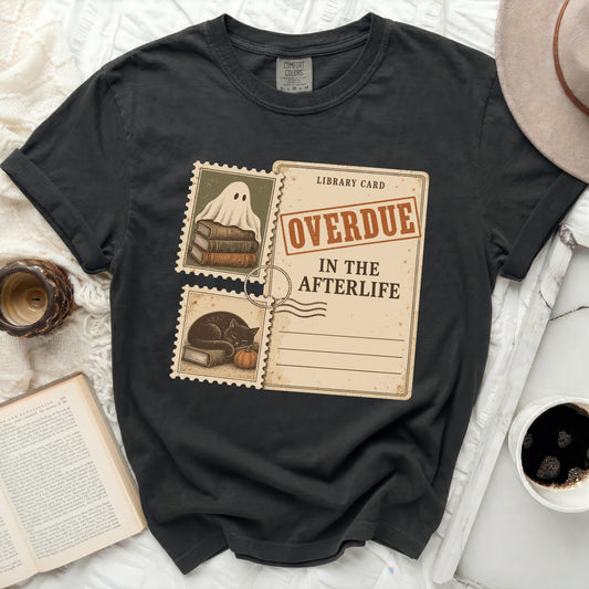 Black t-shirt with a library card graphic featuring a ghost, cat, and "OVERDUE IN THE AFTERLIFE" text.