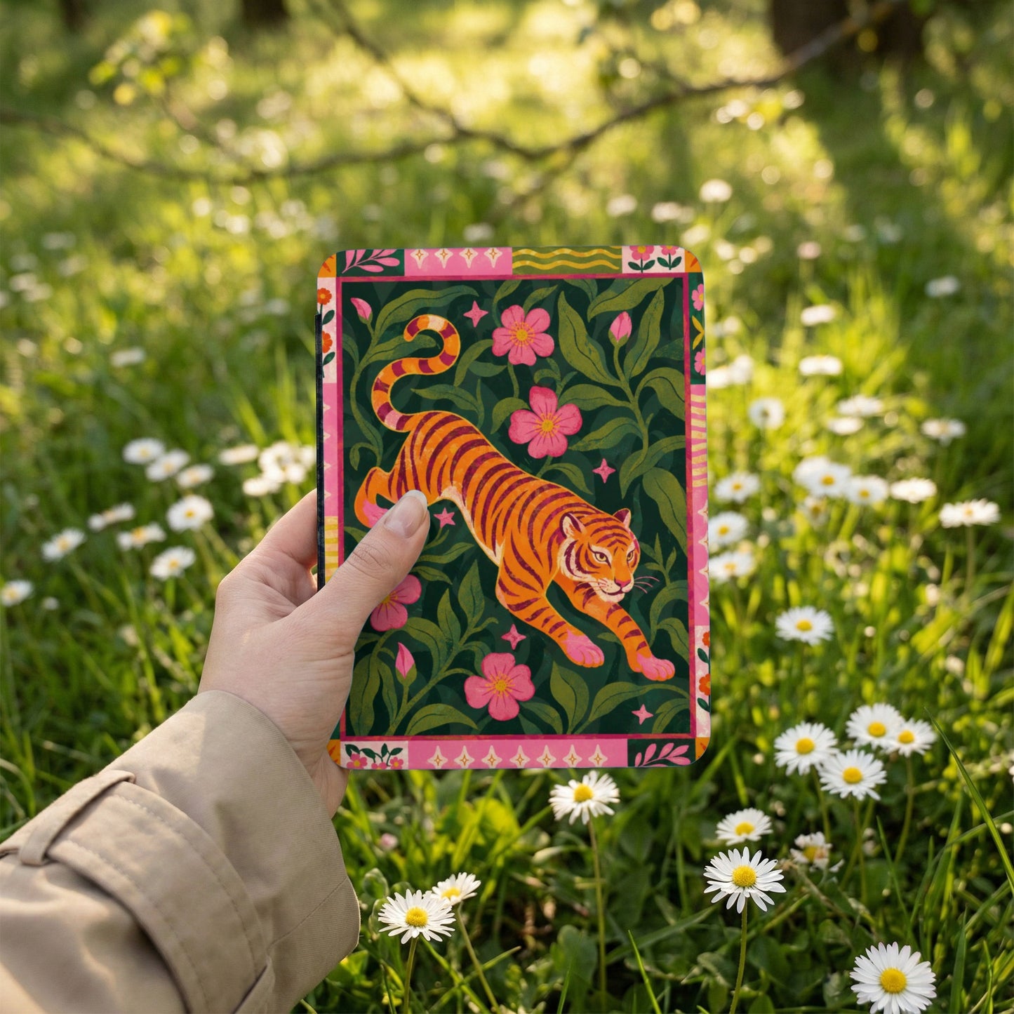 Illustration of a tiger with pink flowers on a dark green background held in a hand.