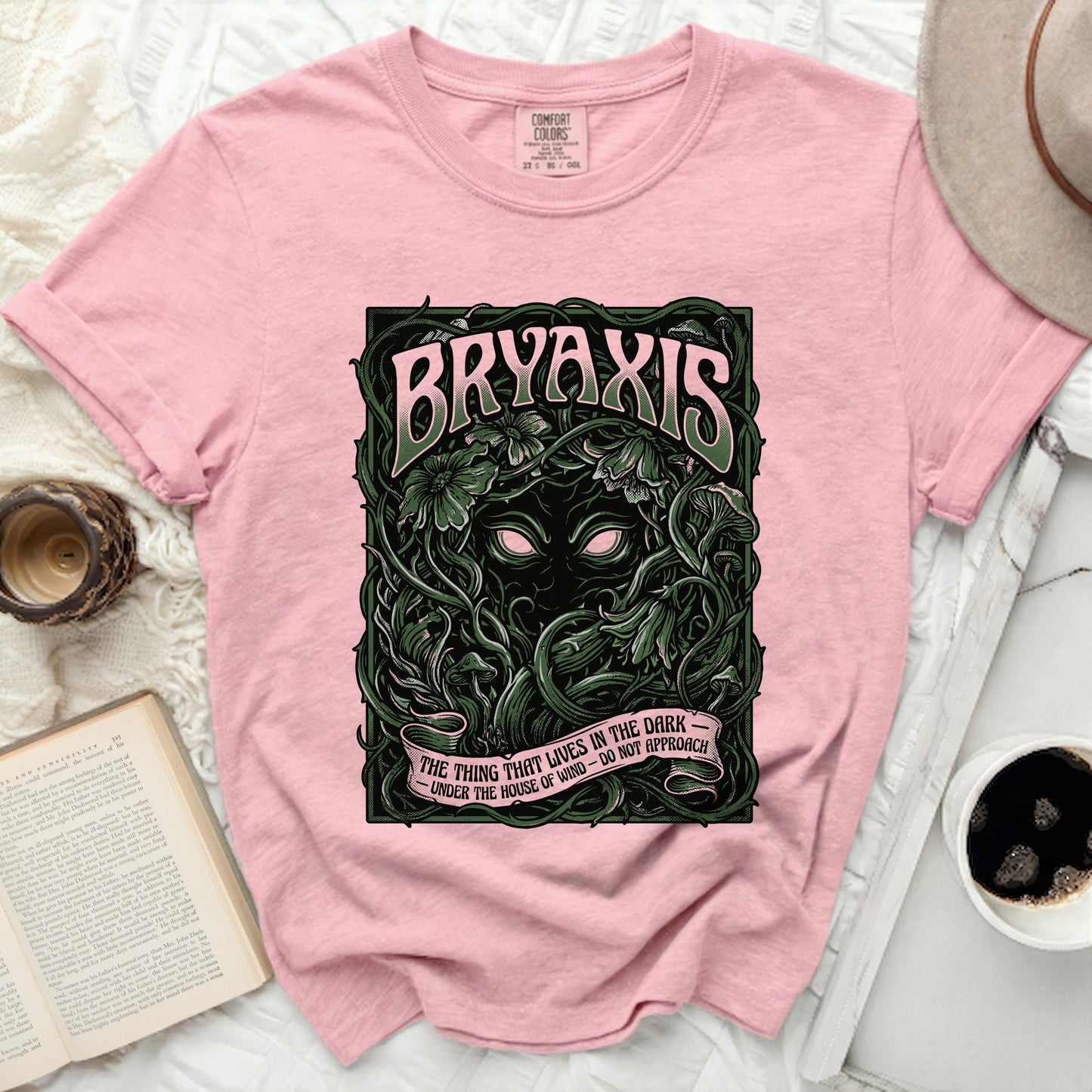 Pink t-shirt with "BRYAXIS" and "THE THING THAT LIVES IN THE DARK" text.