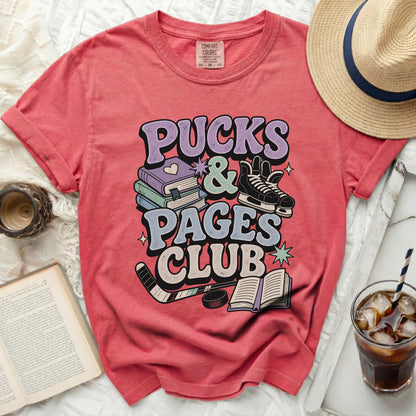 Coral t-shirt with "Pucks & Pages Club" text and hockey and book graphics.