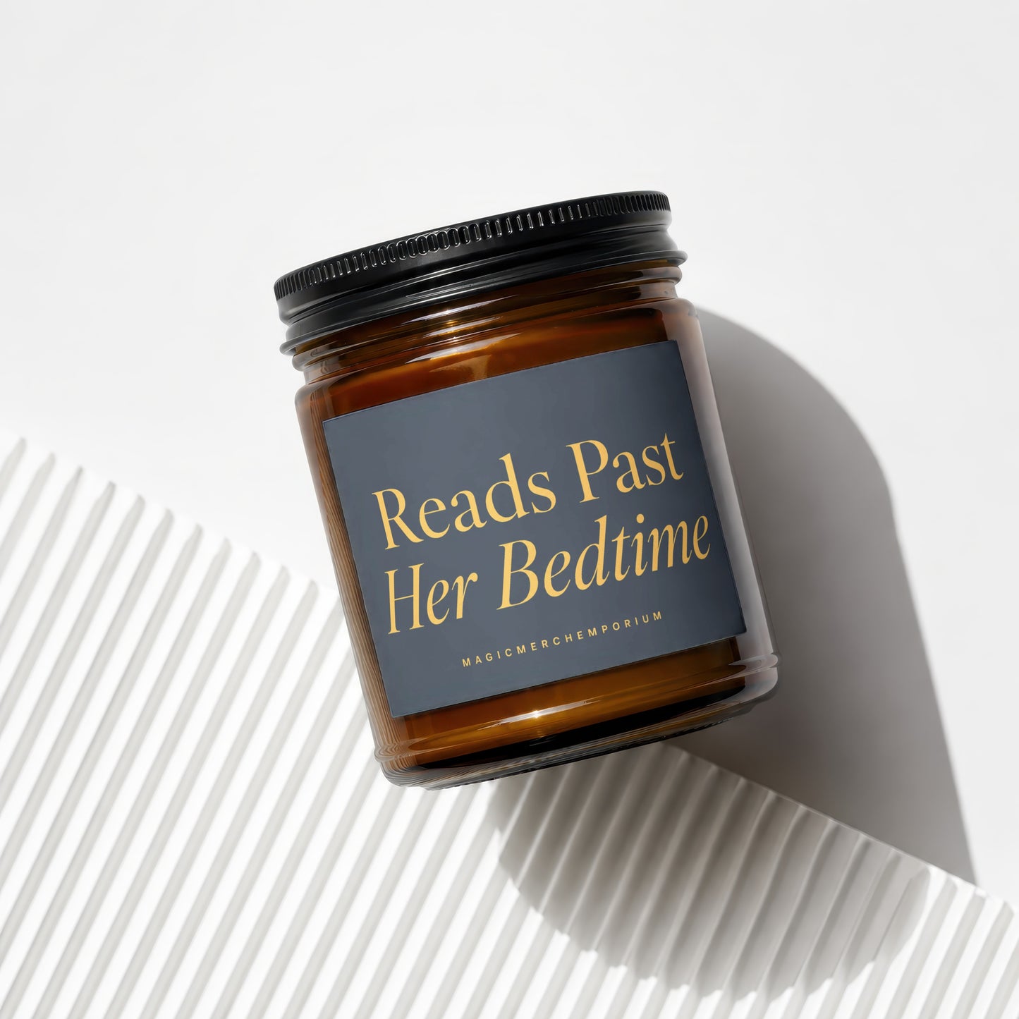 Candle with black lid and label reading "Reads Past Her Bedtime".