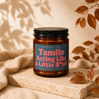 Amber candle with blue label reading "Smells Like Tamlin Acting Like a Little B*tch".