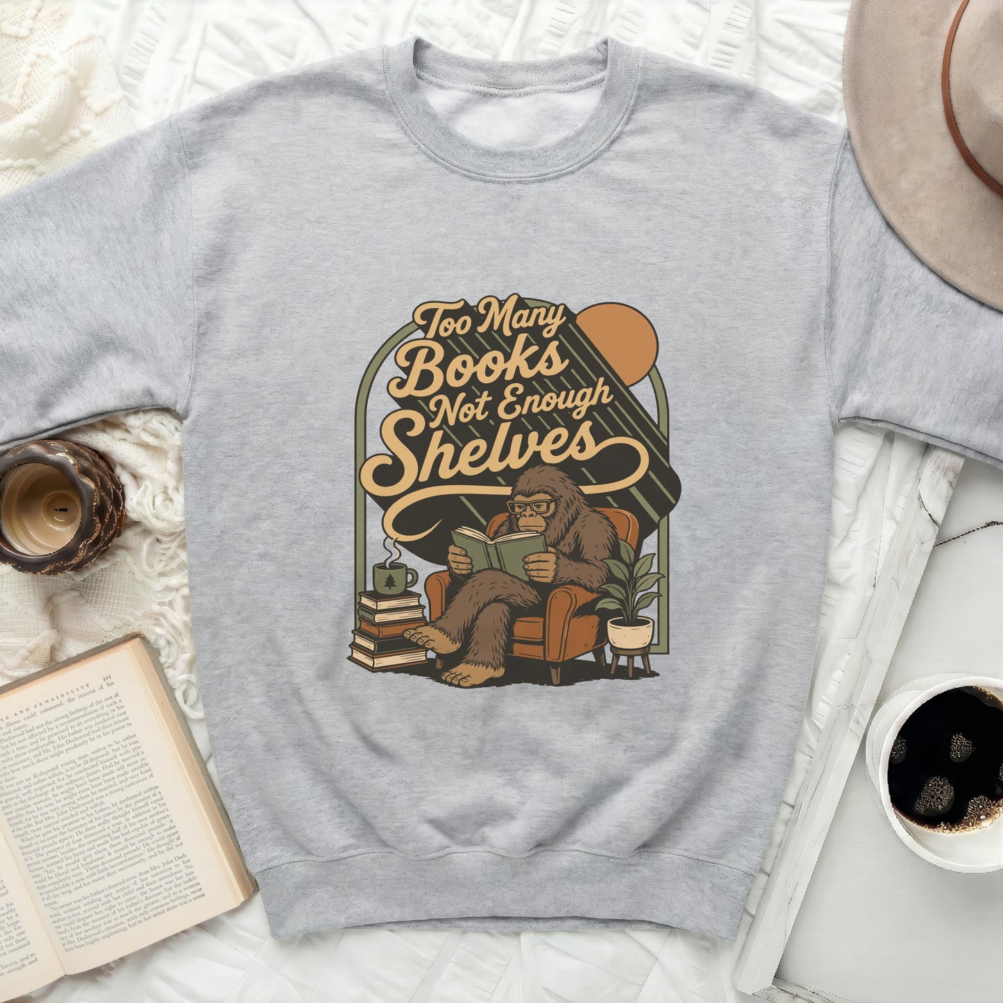 Graphic of Bigfoot reading in a chair with text: Too Many Books Not Enough Shelves.