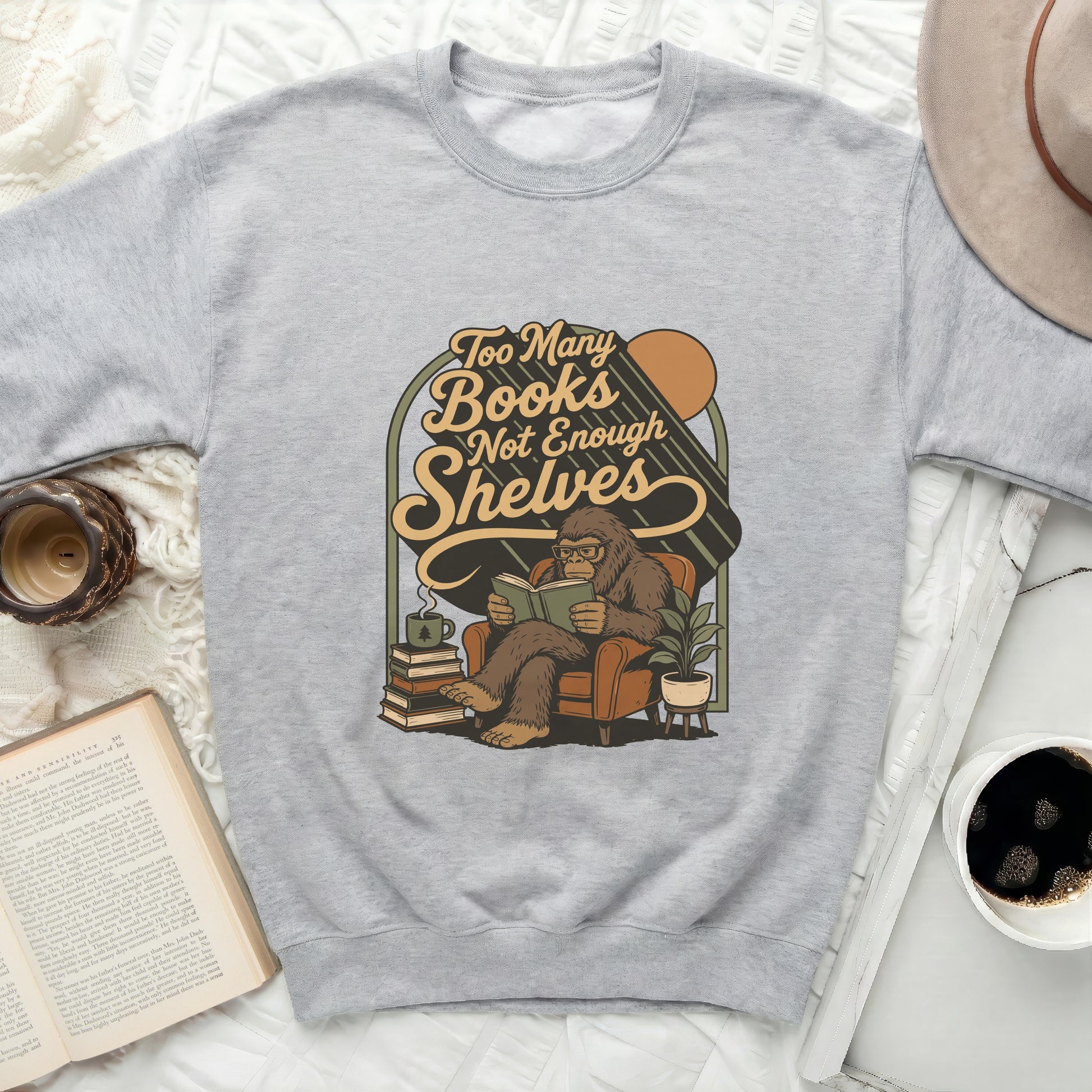 Graphic of Bigfoot reading in a chair with text: Too Many Books Not Enough Shelves.