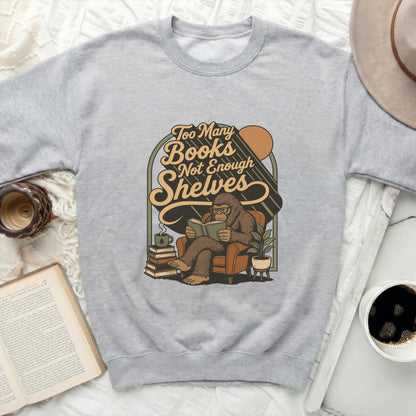Graphic of Bigfoot reading in a chair with text: Too Many Books Not Enough Shelves.
