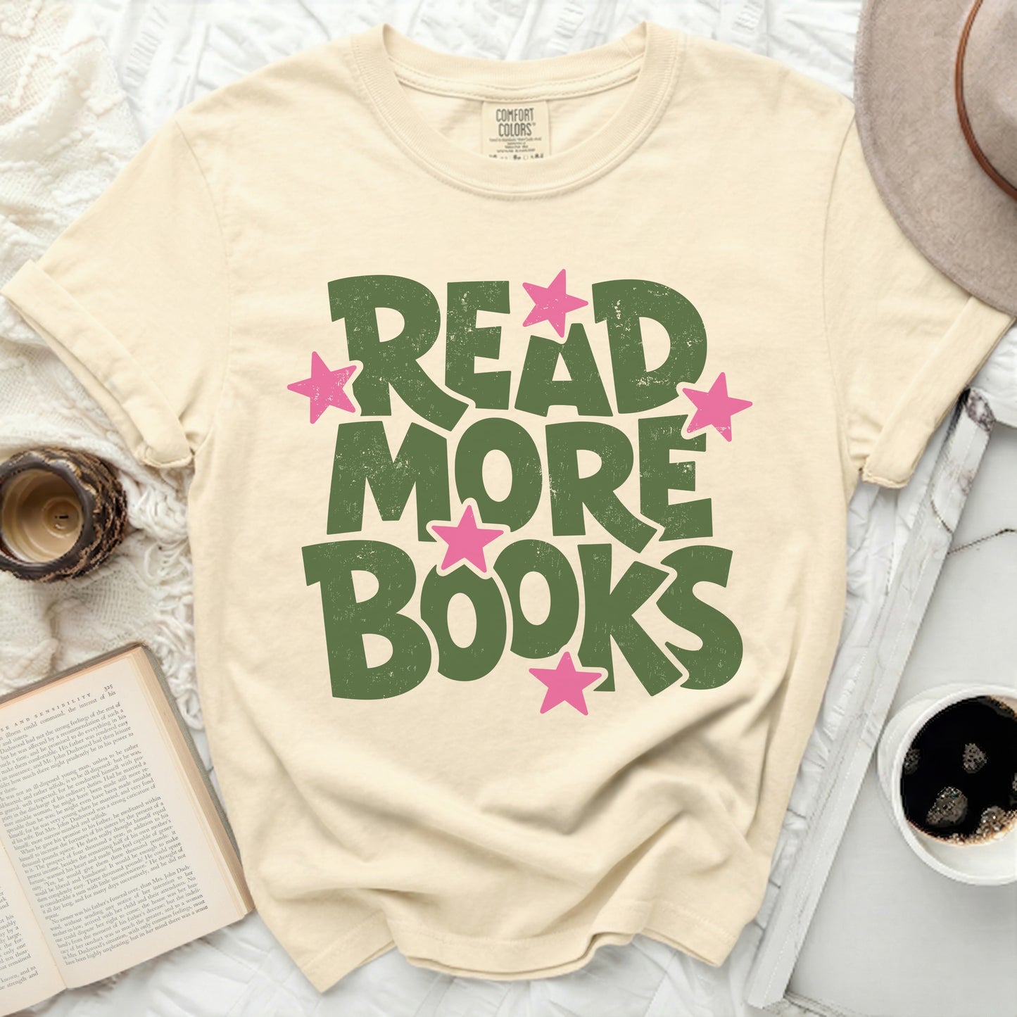 Cream t-shirt with "Read More Books" in green distressed lettering and pink stars.