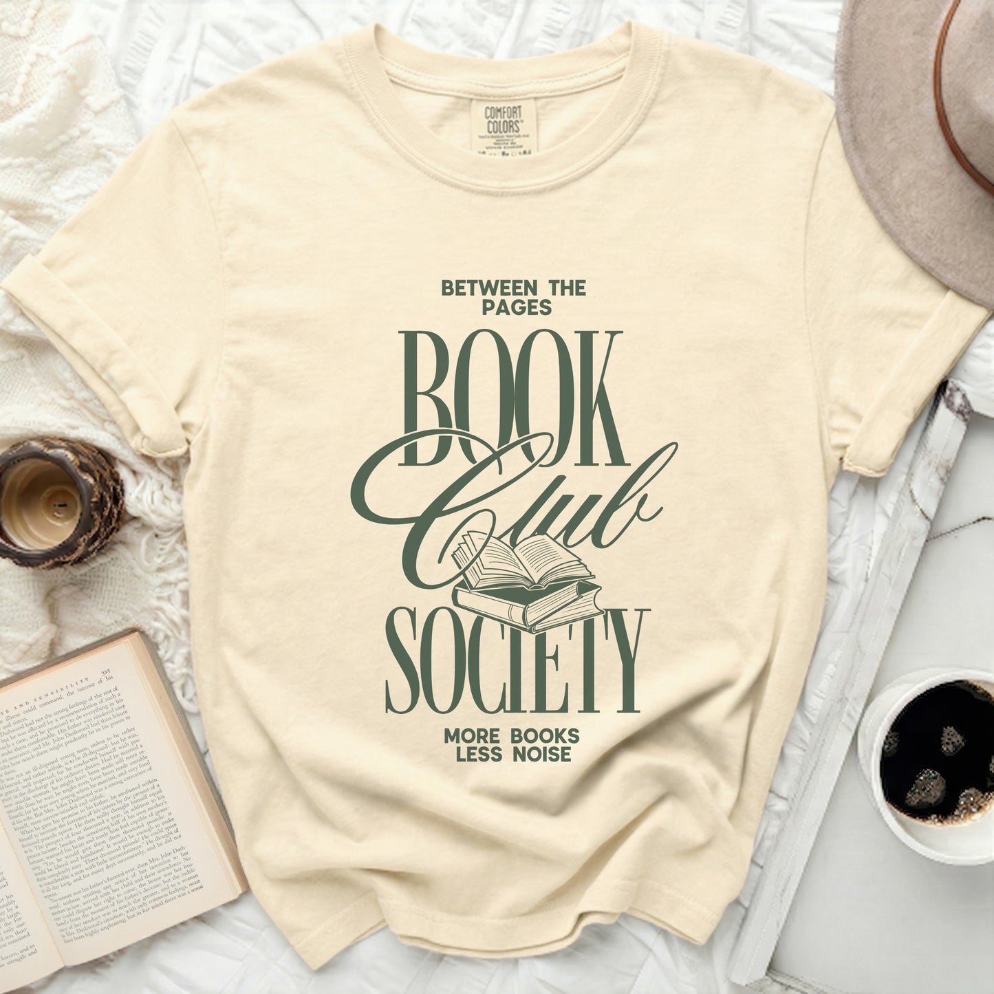 Cream t-shirt with "Between the Pages Book Club Society" text and graphic.