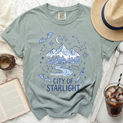 Green t-shirt with a "City of Starlight" graphic featuring a city, mountains, moon, and stars.