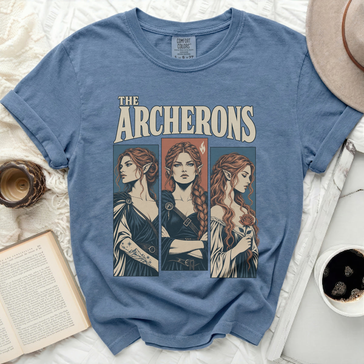 Blue t-shirt with "THE ARCHERONS" text and three illustrated women with pointy ears.