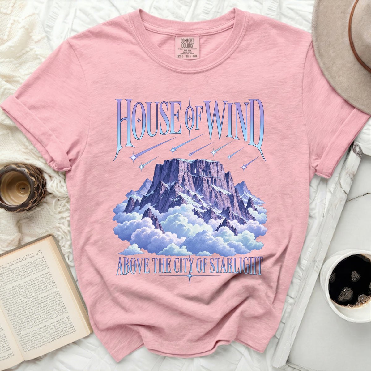 Pink t-shirt with "House of Wind Above the City of Starlight" graphic.