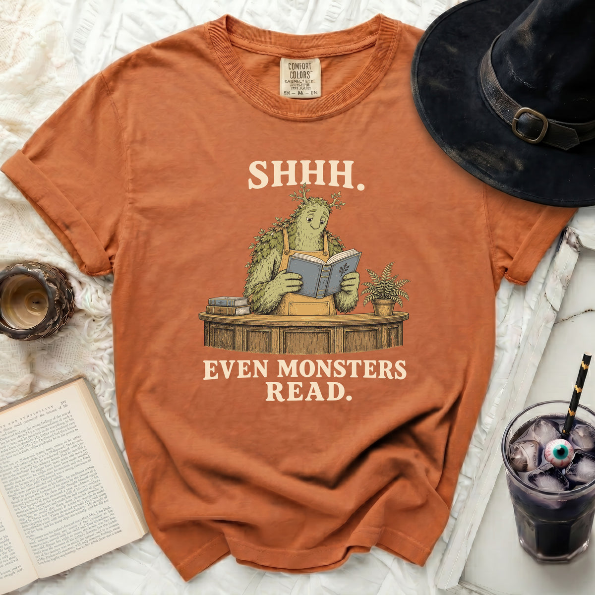 Orange t-shirt with a green monster reading a book, text "SHHH. EVEN MONSTERS READ."