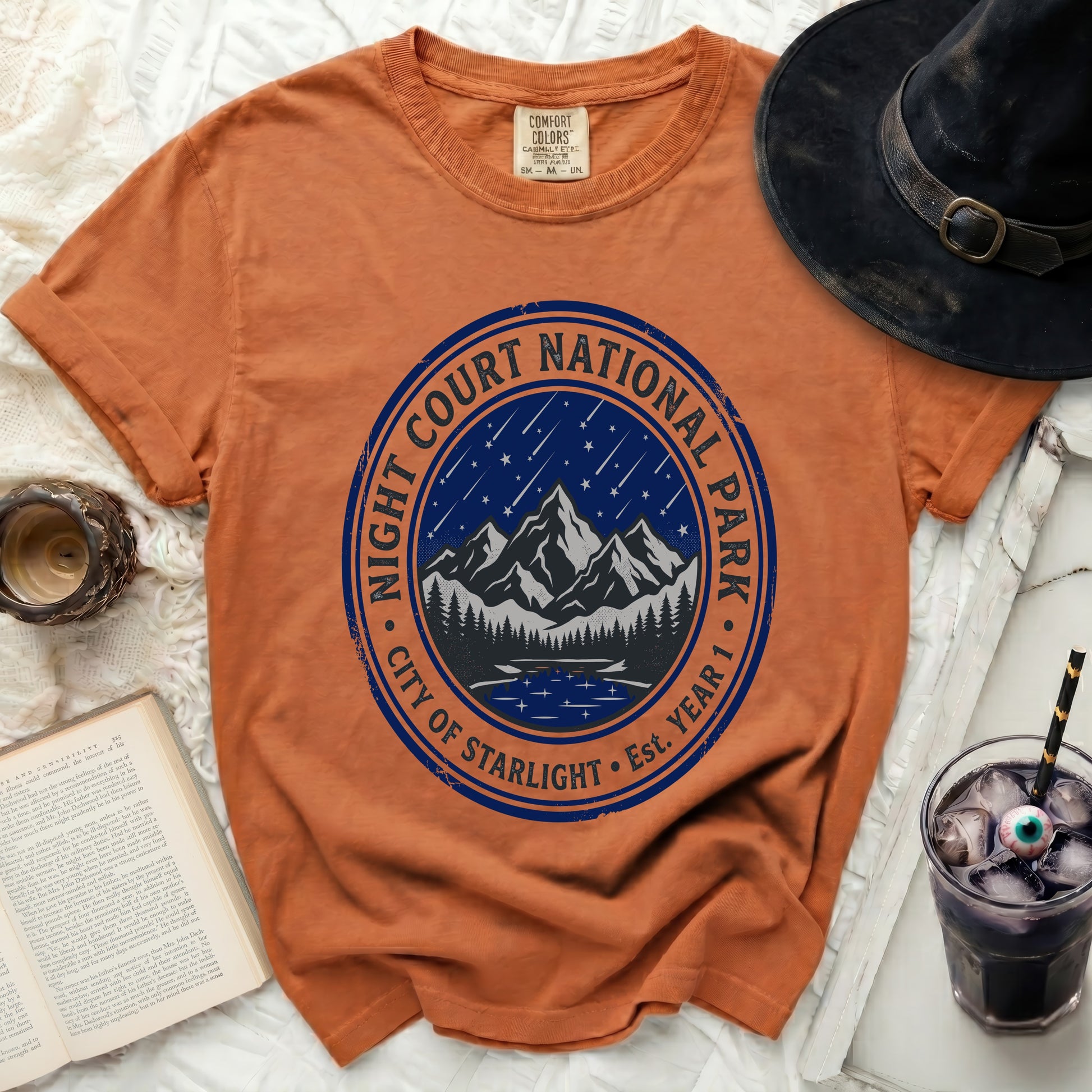 Orange t-shirt with "Night Court National Park City of Starlight" circular graphic.