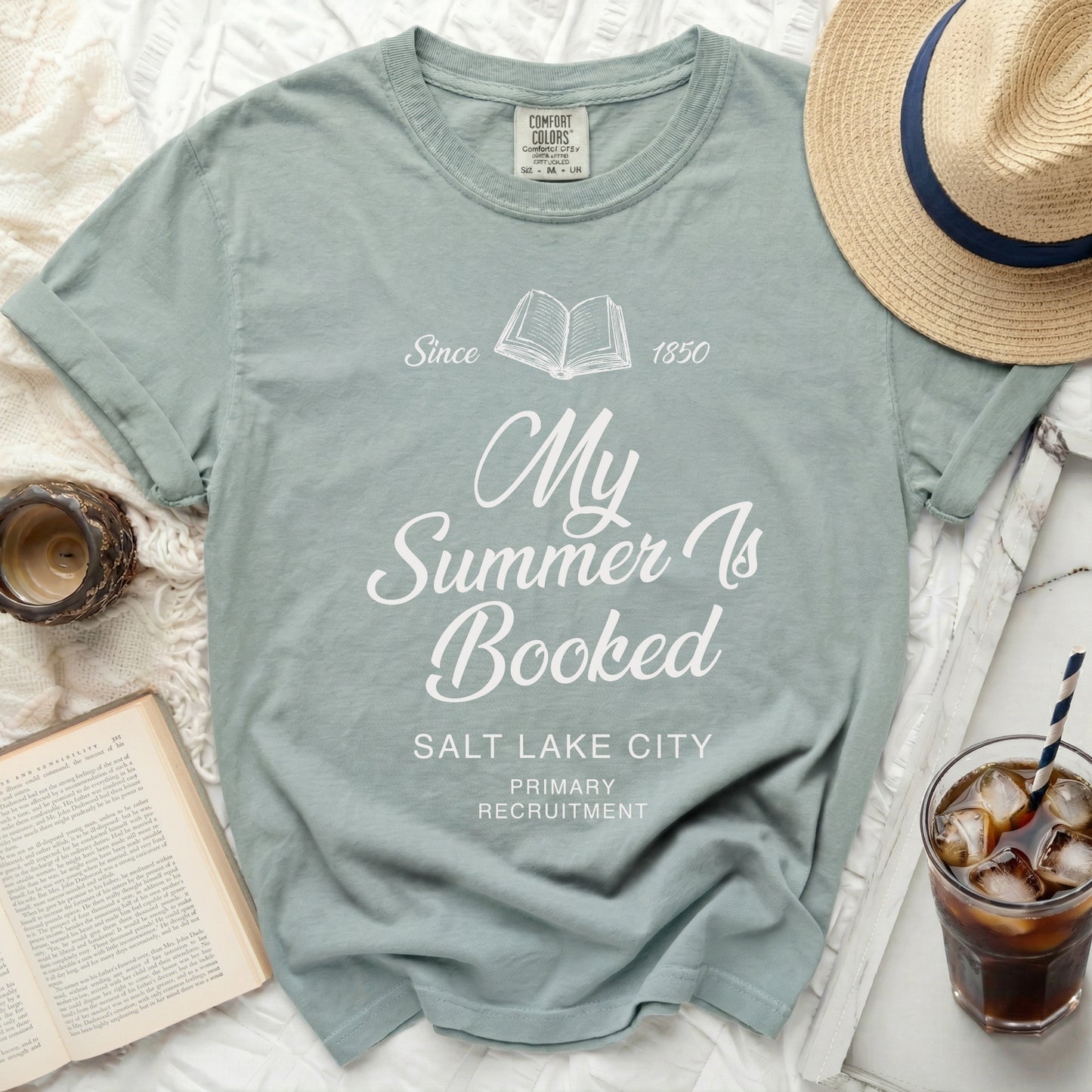 Light blue t-shirt with "My Summer Is Booked" text and book graphic.