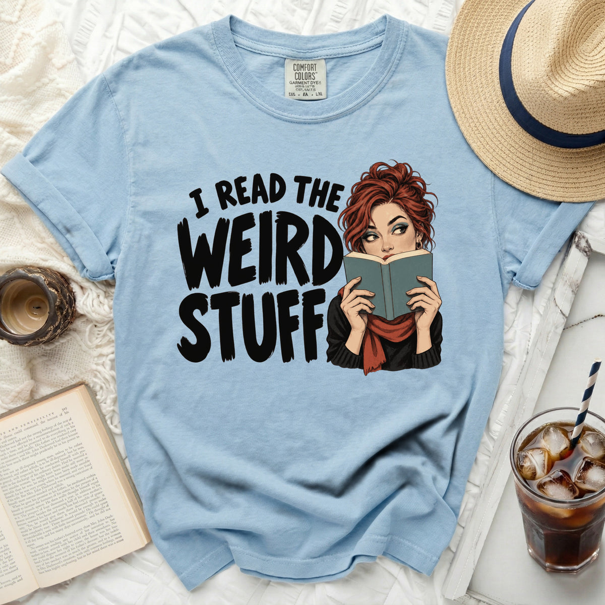 Light blue t-shirt with "I READ THE WEIRD STUFF" text and illustration of a woman reading.