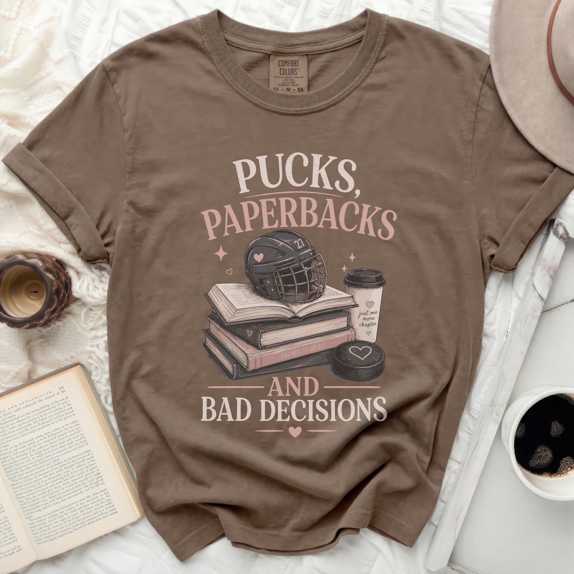 Brown t-shirt with "Pucks, Paperbacks, and Bad Decisions" text and hockey graphics.