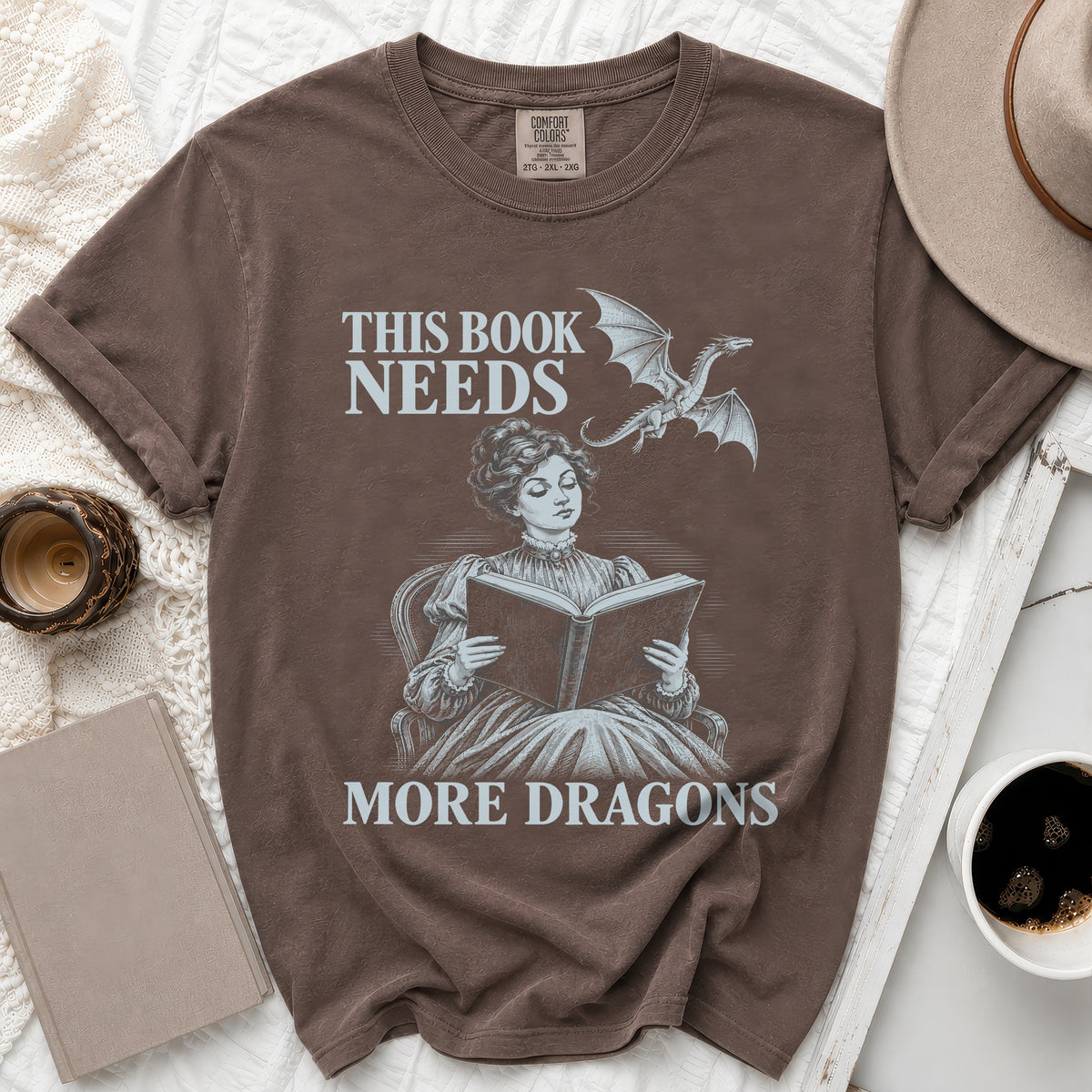 Brown t-shirt with "This Book Needs More Dragons" text and dragon graphic.