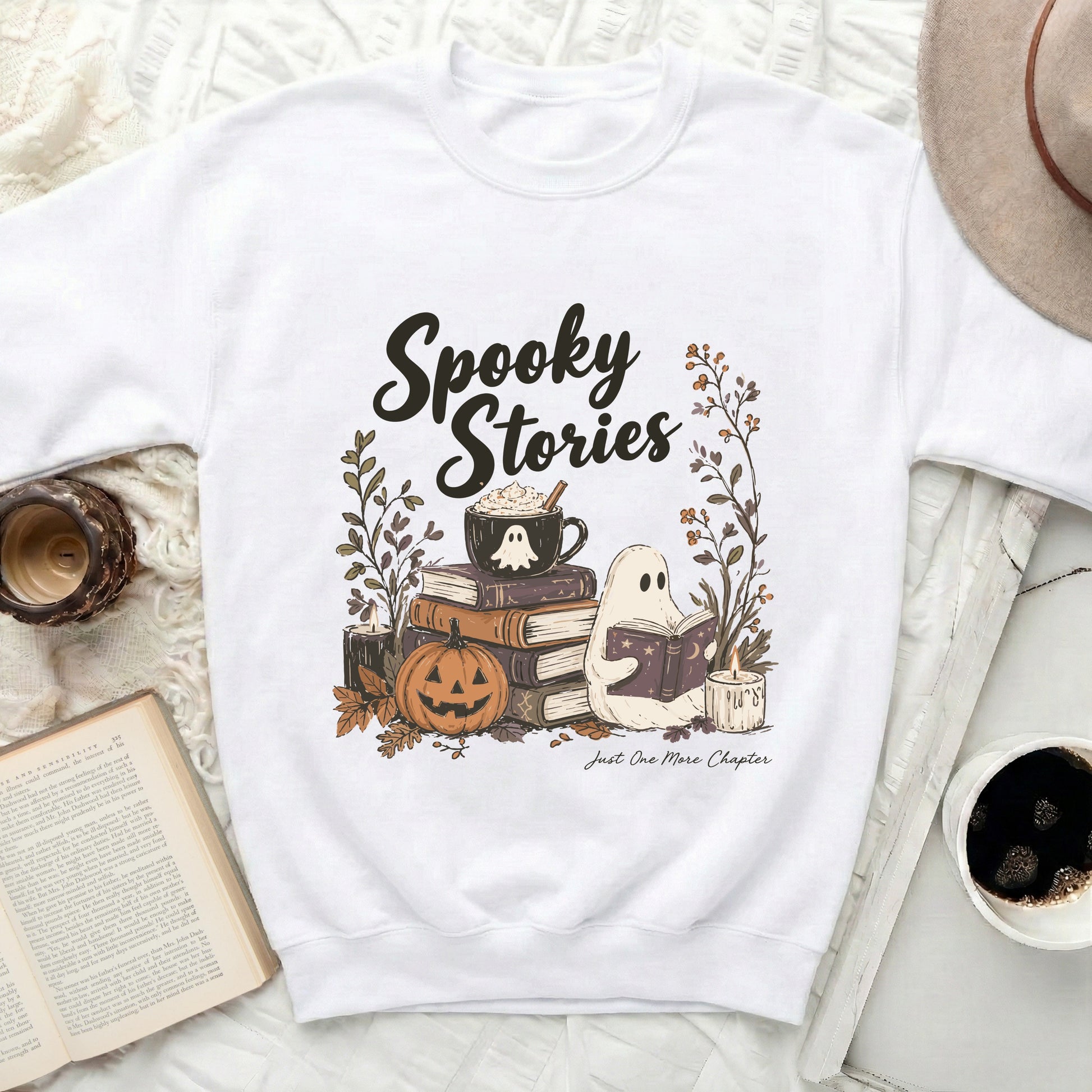 White sweatshirt with "Spooky Stories" and ghost reading among books and pumpkin.