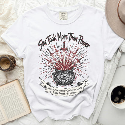 White t-shirt with "She Took More Than Power" and cauldron graphic.