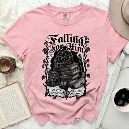 Pink t-shirt with "Falling For Him" text, hockey gear, and books.