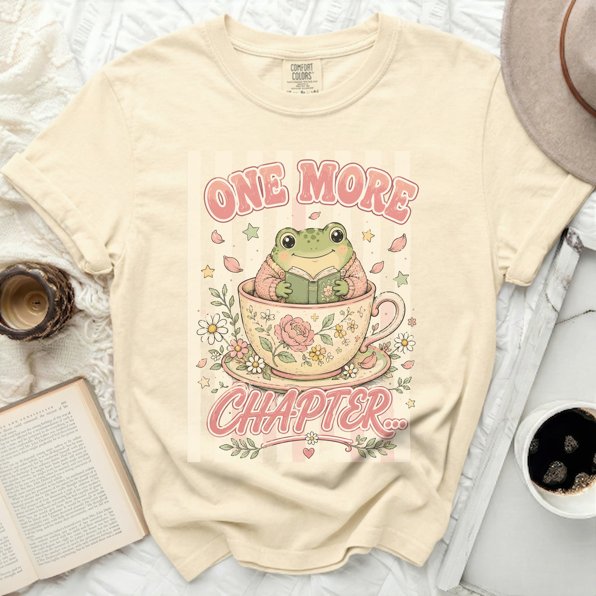 T-shirt with frog in teacup reading "ONE MORE CHAPTER" graphic.