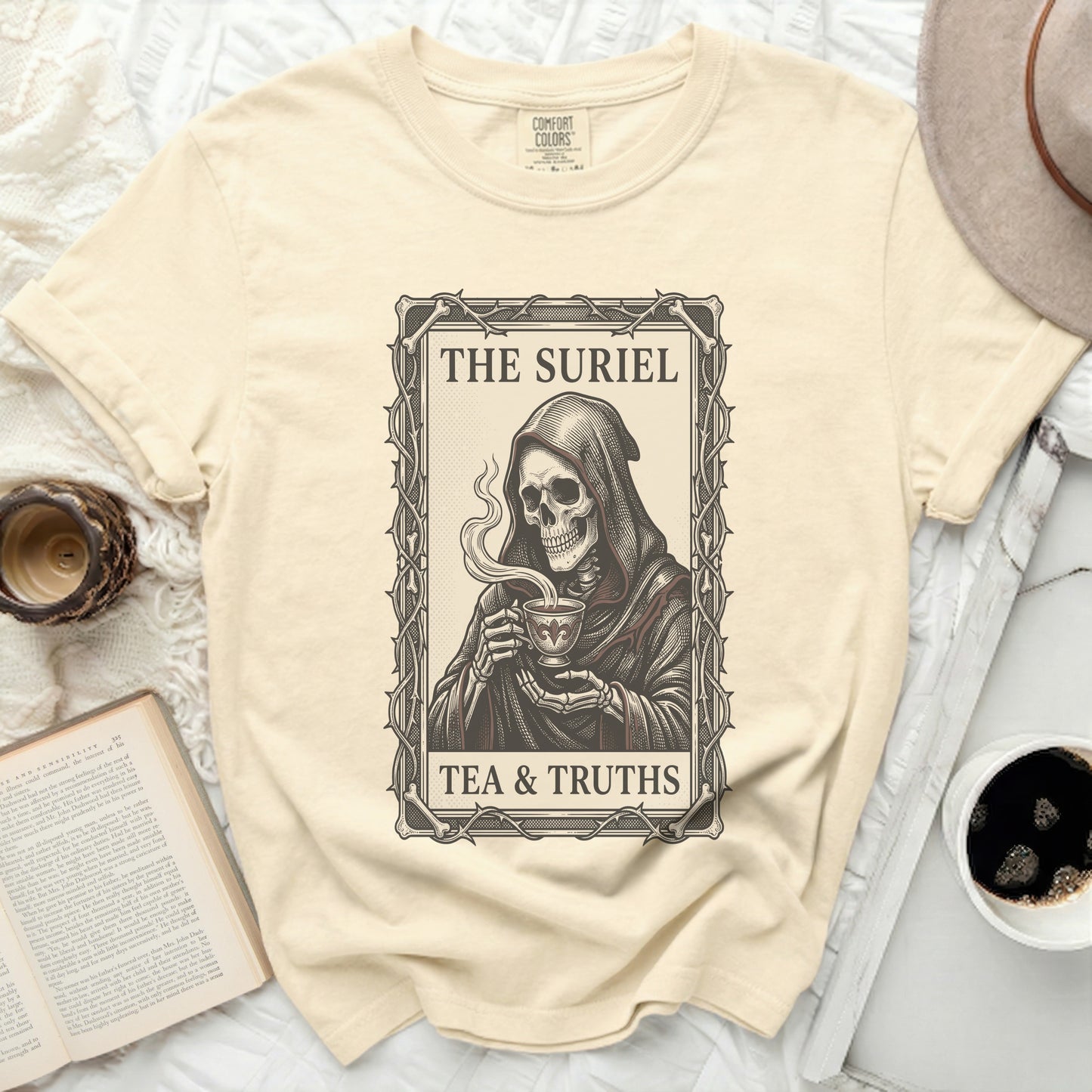 Cream t-shirt with Grim Reaper holding a teacup, reading "The Suriel Tea & Truths".