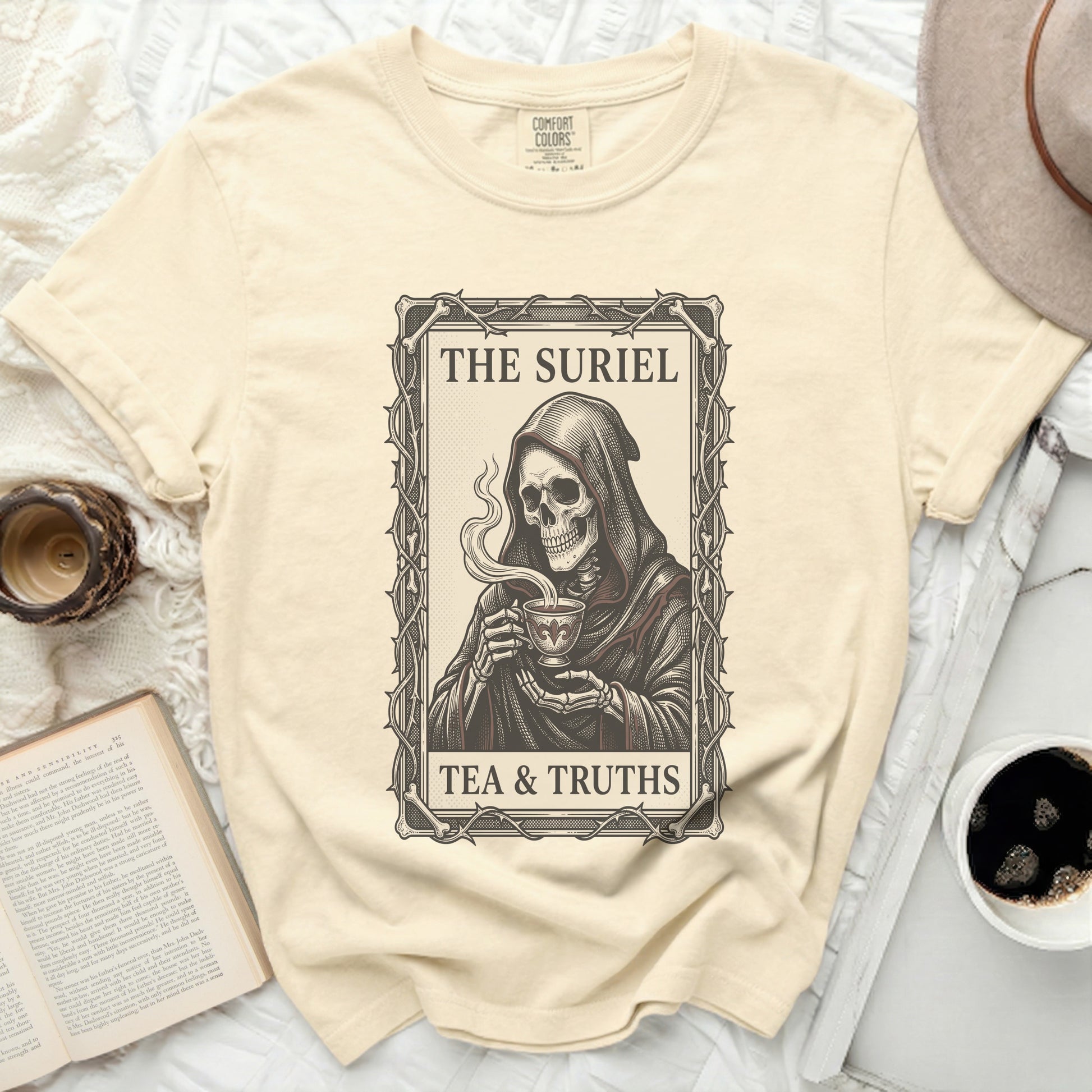 Cream t-shirt with Grim Reaper holding a teacup, reading "The Suriel Tea & Truths".